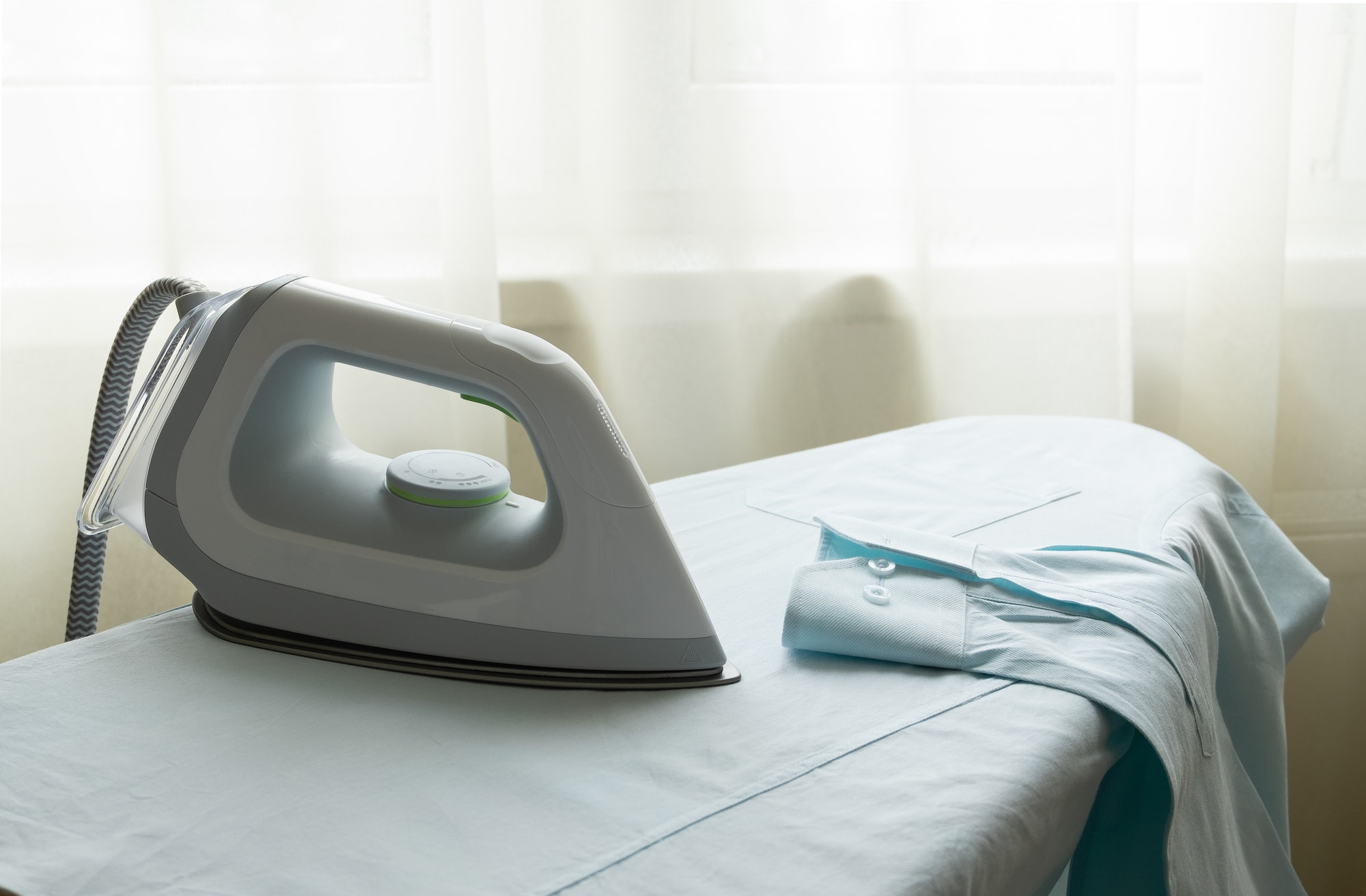 An electric iron stands on an ironing board.