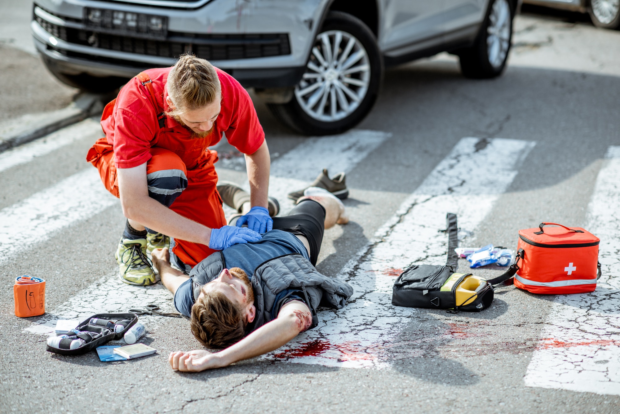 Medic applying emergency care to the injured man on the road