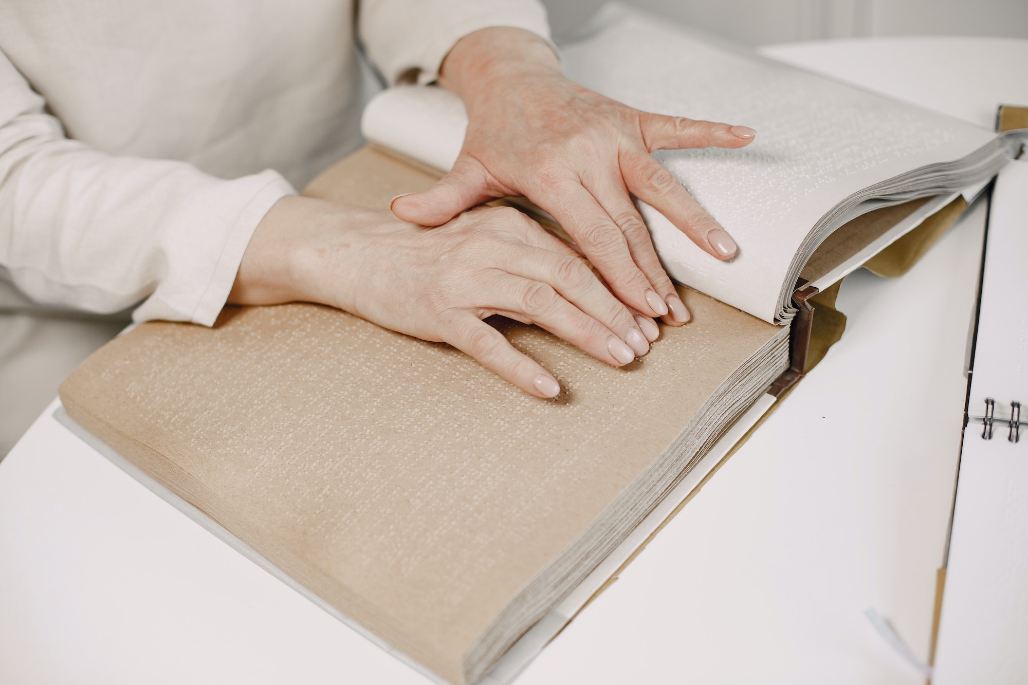 Blind mature woman reading braille book at home