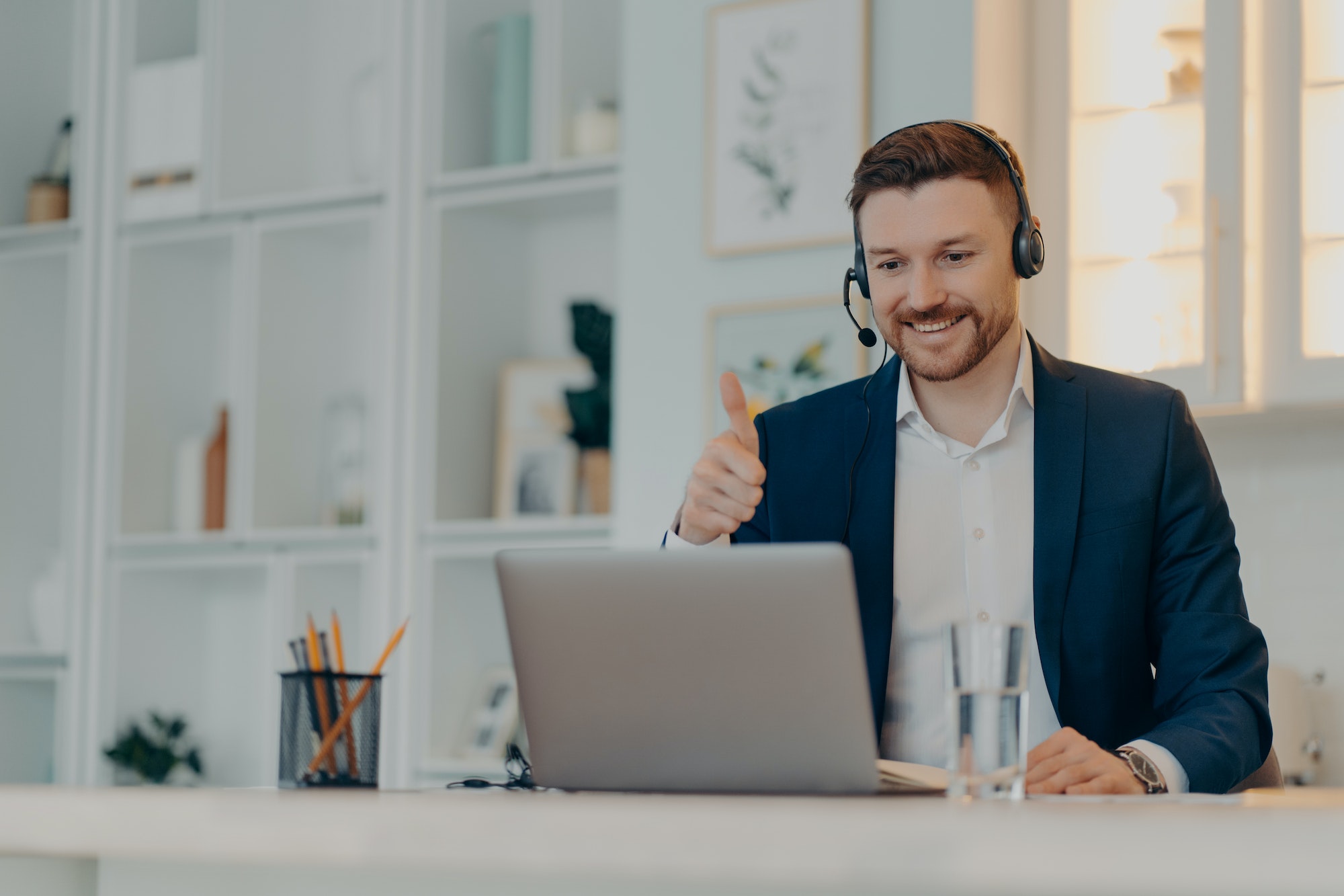 Happy young man showing thumb up while having video conference