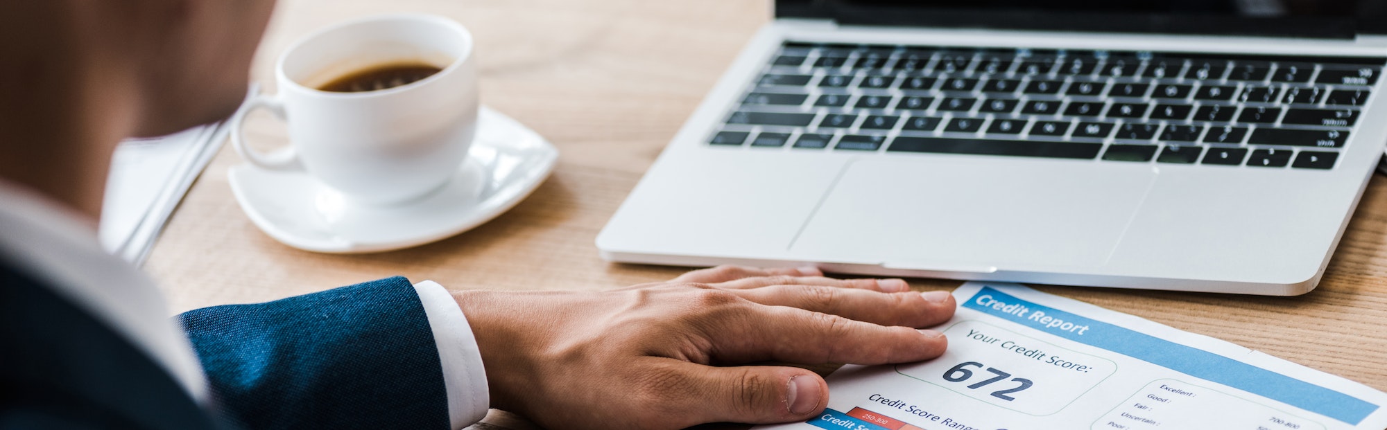 panoramic shot of man near paper with credit report letters and cup of coffee