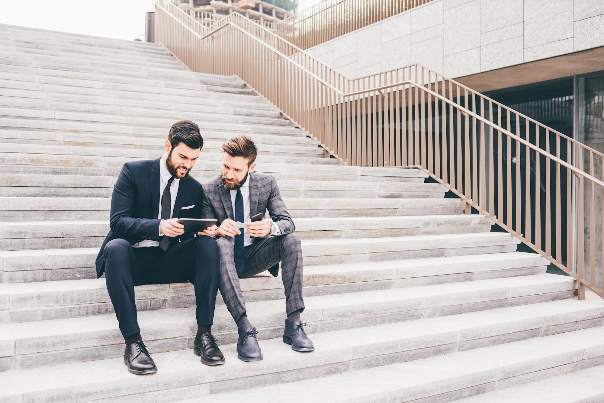 Two contemporary businessman using devices